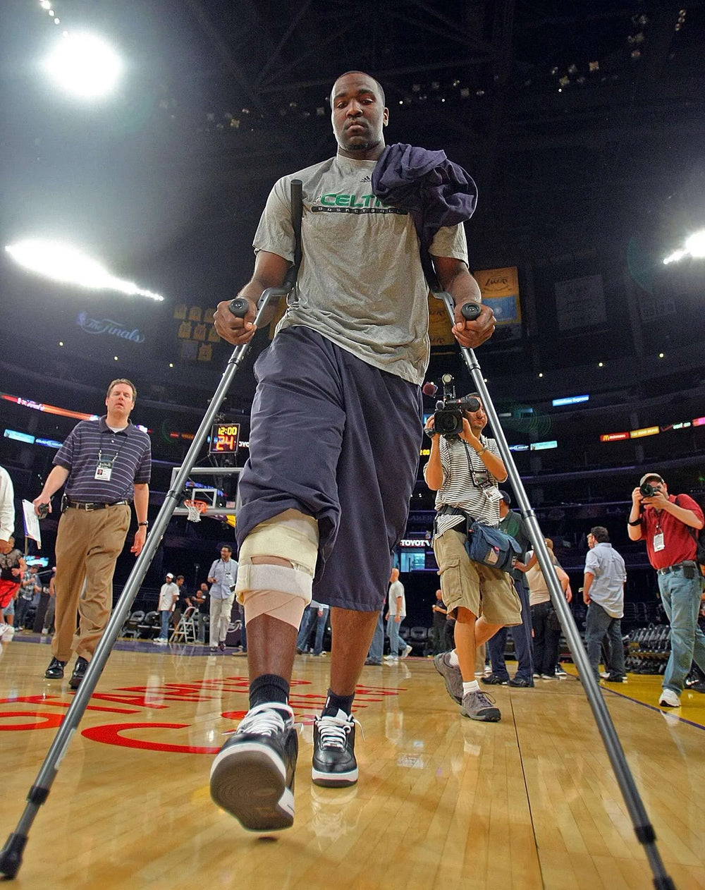 Injured player on crutches on basketball court.