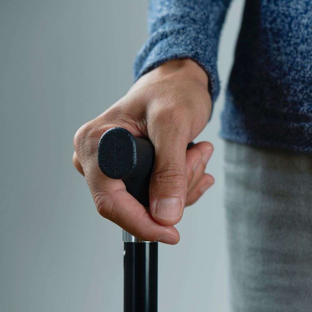 Hand gripping walking cane handle.