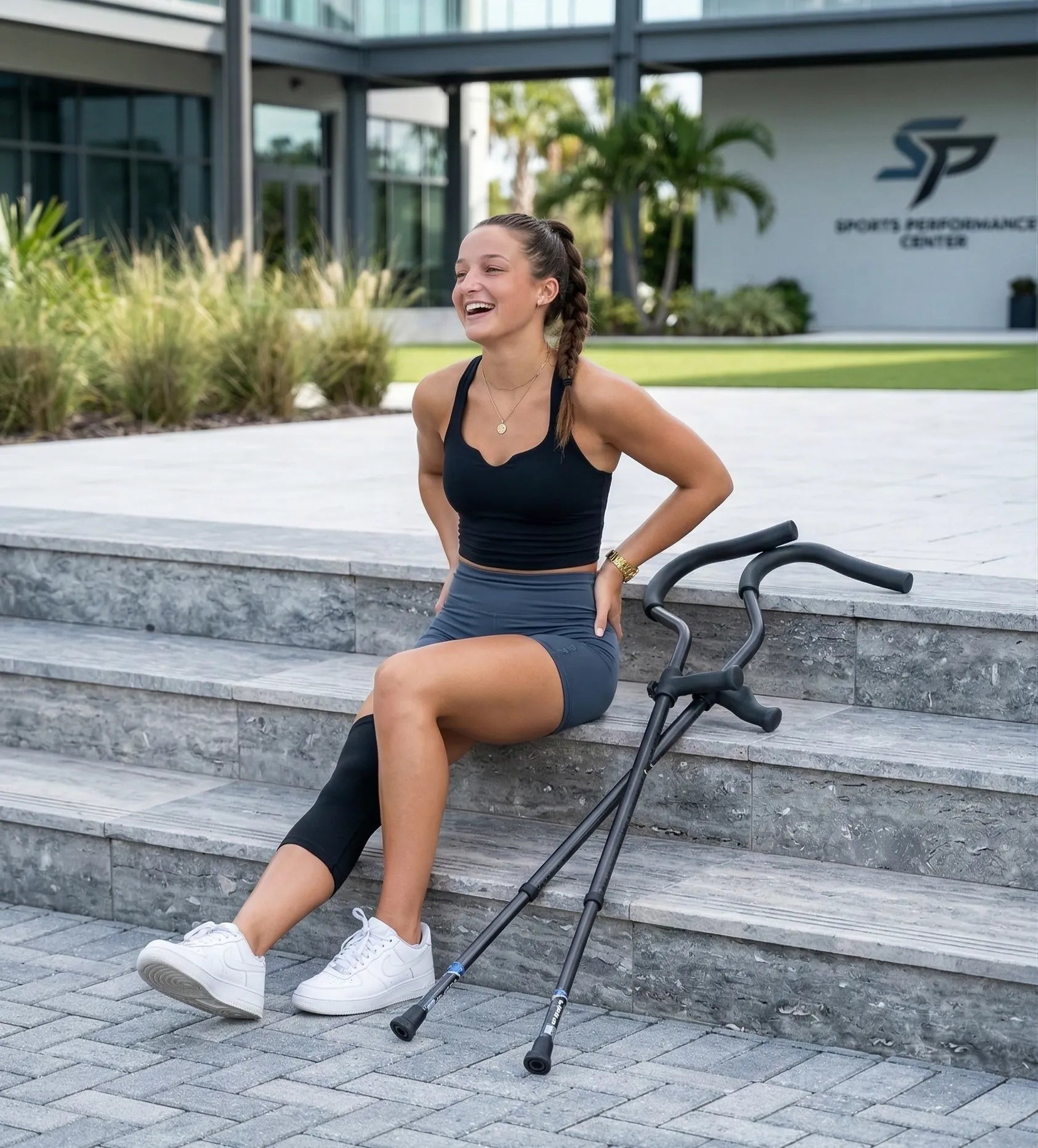 Woman with crutches sitting and smiling outside.
